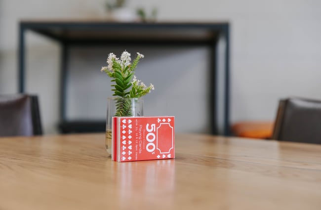 Close up of playing cards and flower on a table.