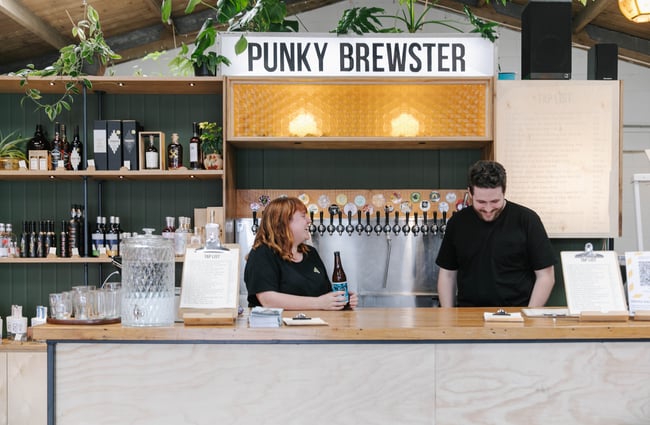 Woman and man behind the bar smiling.