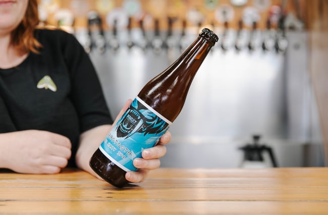 Woman holding bottle of beer at the bar.