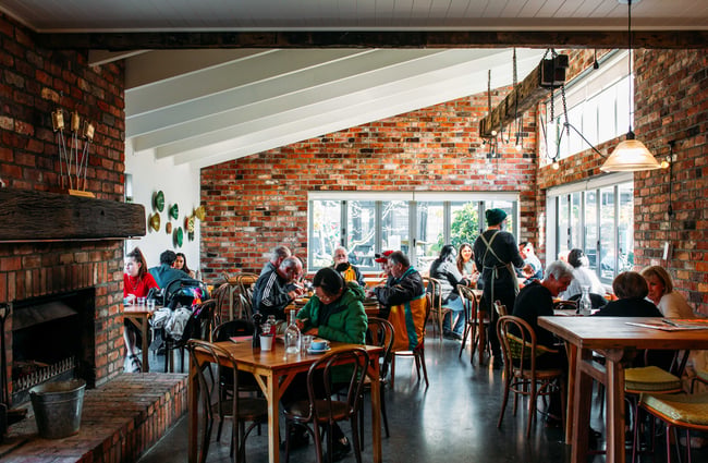 Tables full of customers inside a room lined with old red bricks.