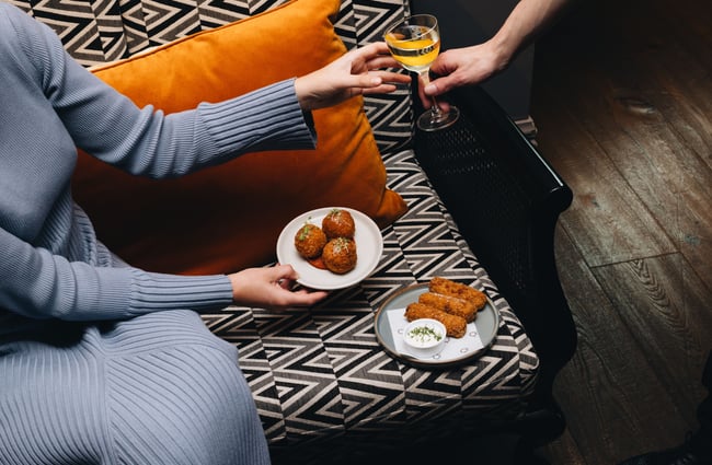 Hands holding arancini and champagne.