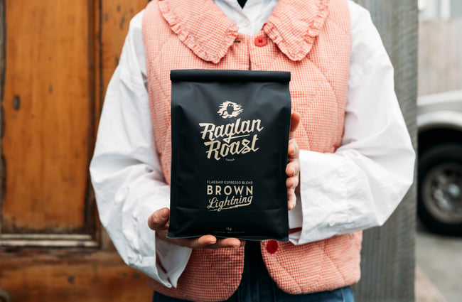 Hands holding a bag of roasted coffee beans.