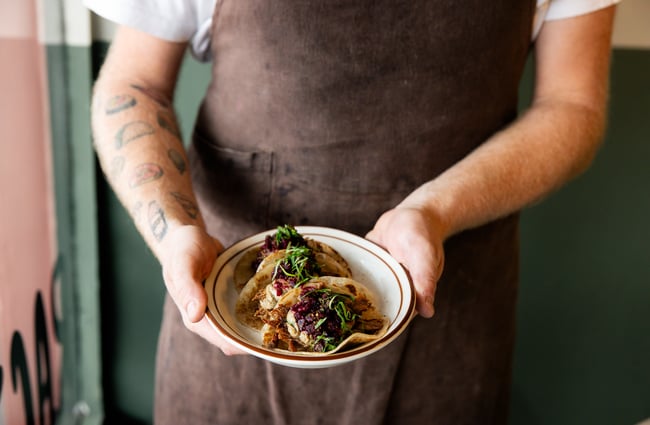 Hands holding a small plate of food.