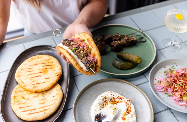 Customer holding a pita bread with fillings at The Rambler.