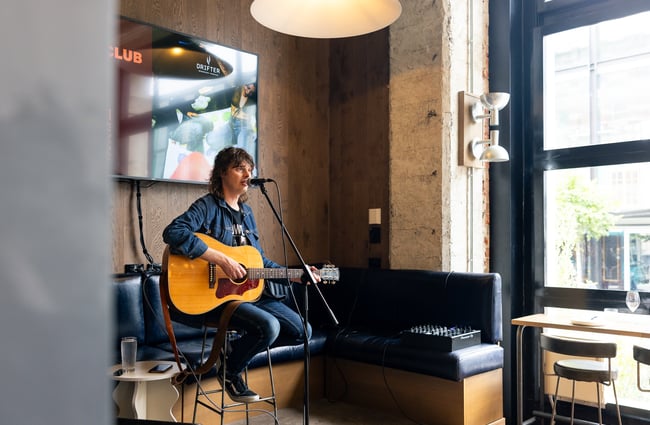 Musician playing the guitar in front of a microphone at The Rambler.