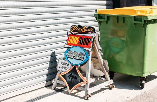 A surf shop sign on a footpath.