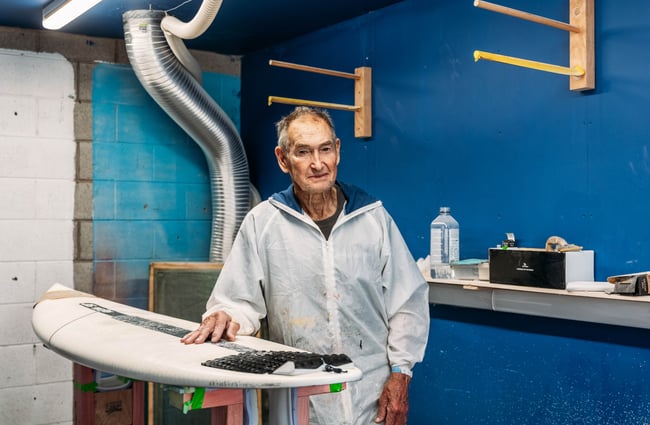 A man standing next to a surf board.
