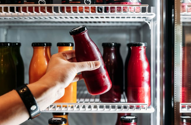 Bottle of fresh juice being taken out of the fridge at Recharge Bar & Cafe.