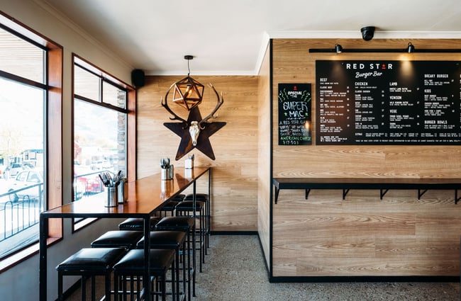 Stag skull mounted on a star on a wall and a large menu on another wall at Red Star, Wānaka.