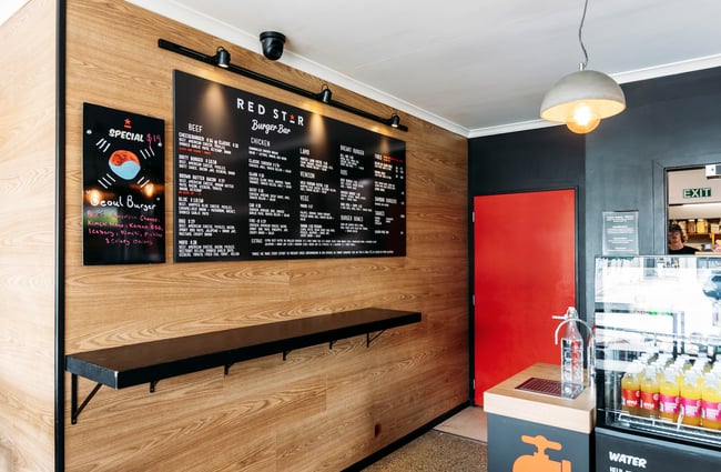 The menu on a black panel on the wall and the counter and drinks fridge at Red Star, Wānaka.