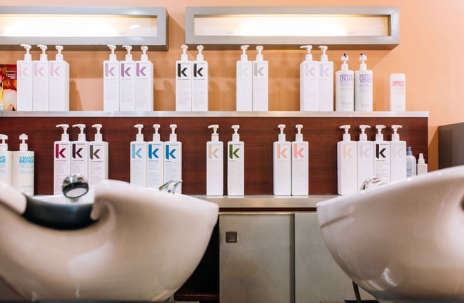 White sinks with a wall of product bottles behind.