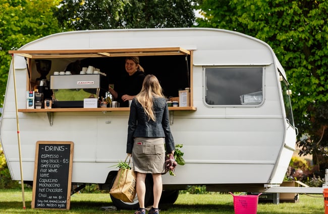 A customer standing outside a food caravan at a market.