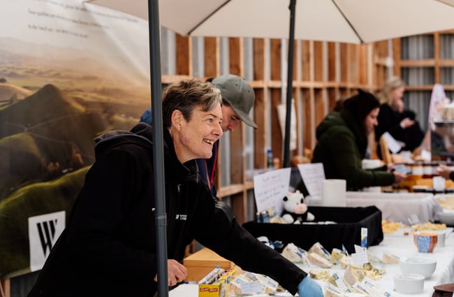 A woman smiling behind a market stall.