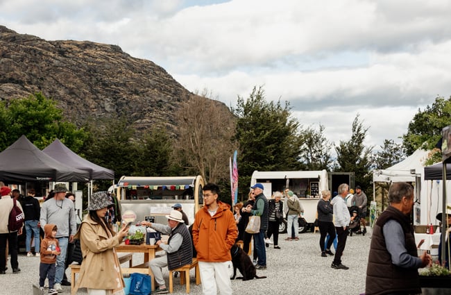 People walking around market stalls outside.