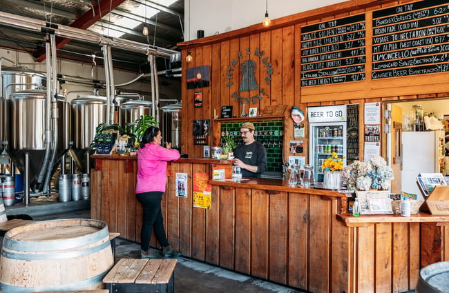 A woman ordering at the timber-clad bar at Rhyme x Reason, Wānaka.