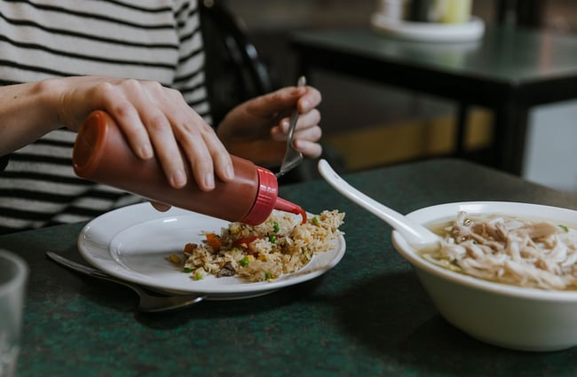 Hot sauce being poured on to rice.