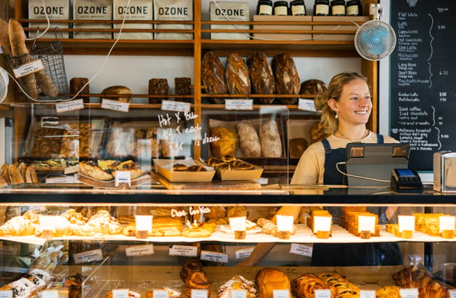 Bakery staff behind the counter and cabinet of pastries.