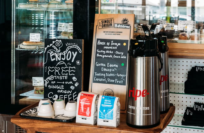Jug of filter coffee next to a sign with coffee notes at cafe counter