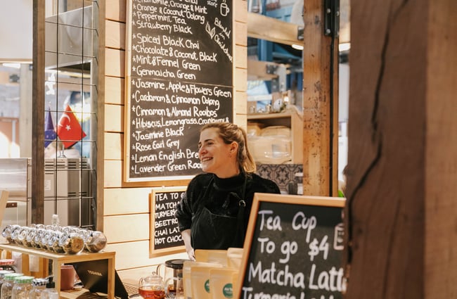 Woman smiling behind coffee counter at Riverside Market.