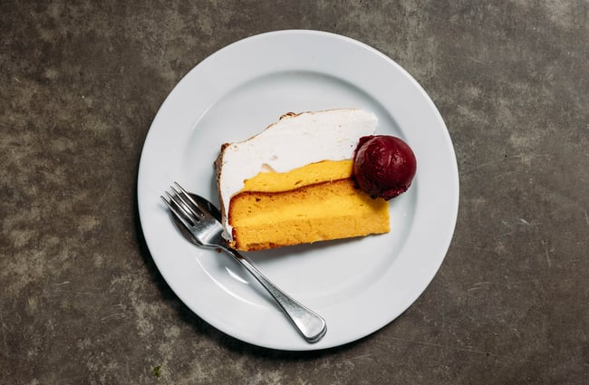 Close up of lemon meringue cake with a scoop of black Doris plum sorbet