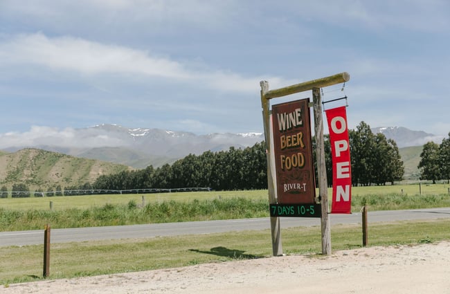 The open sign on the side of the road in front of the River-T Estate winery.