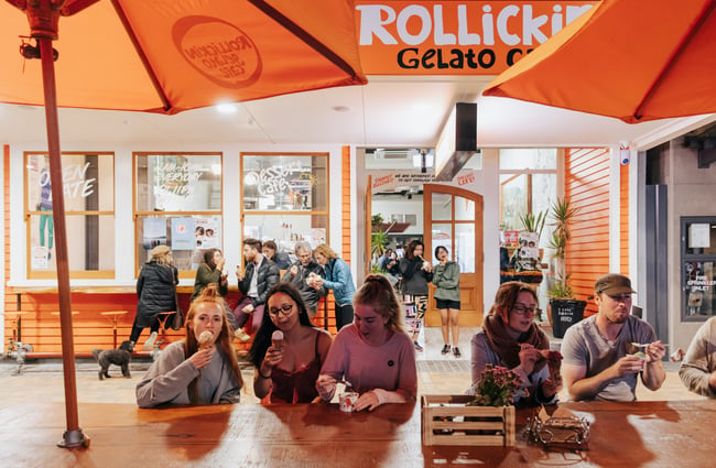 Customers sitting on benches eating ice creams outside Rollickin Gelato.