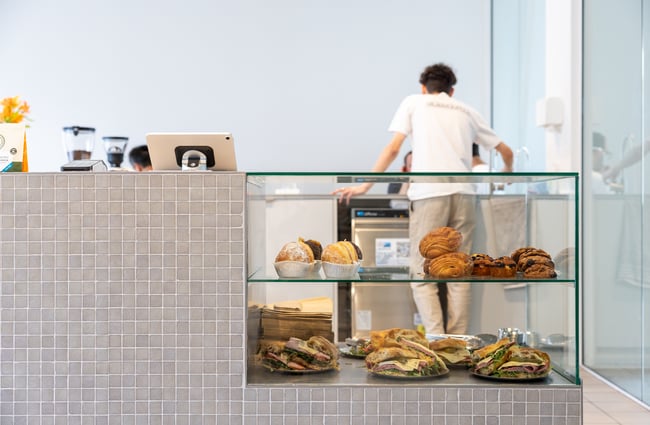 Food in cabinet with barista standing behind the counter at Rook.