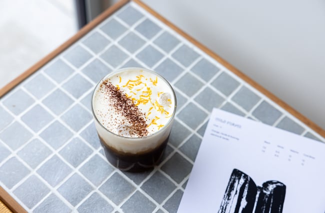 Coffee drink in a glass sitting on a blue tiled table at Rook.