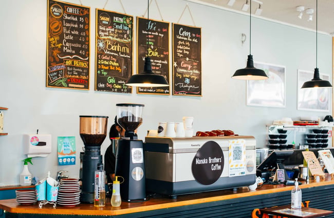 Close up of coffee machine with menu on the wall behind.
