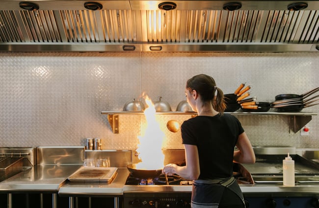 Chef in the kitchen with flaming frying pan at Saikou, Timaru.