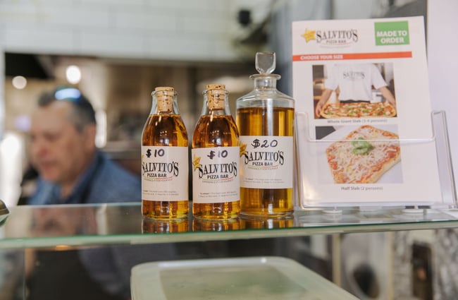 Three bottles of pizza oil on top of the glass cabinet at Salvito's Pizza Bar.