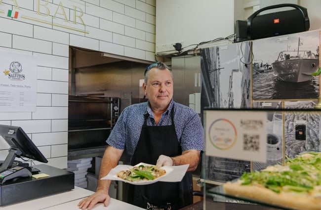 A chef handing a plate with slices of pizza over the counter to a customer.