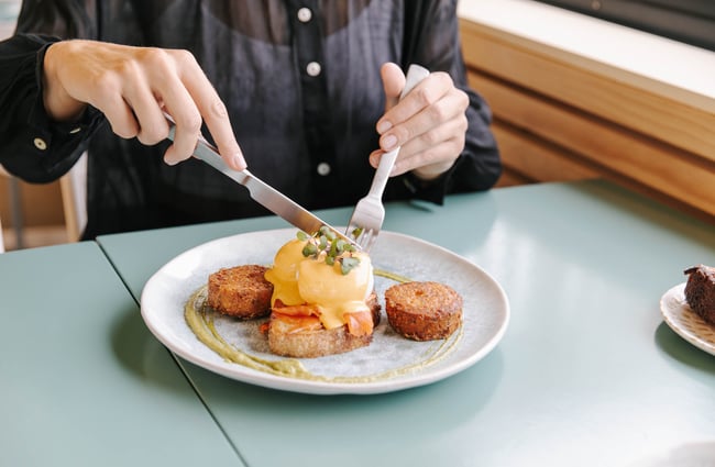 Someone tucking into eggs benedict.