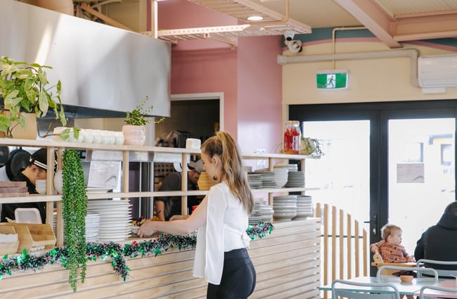Waitress collecting a plate from kitchen.