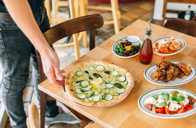Man bringing pizza to the table.