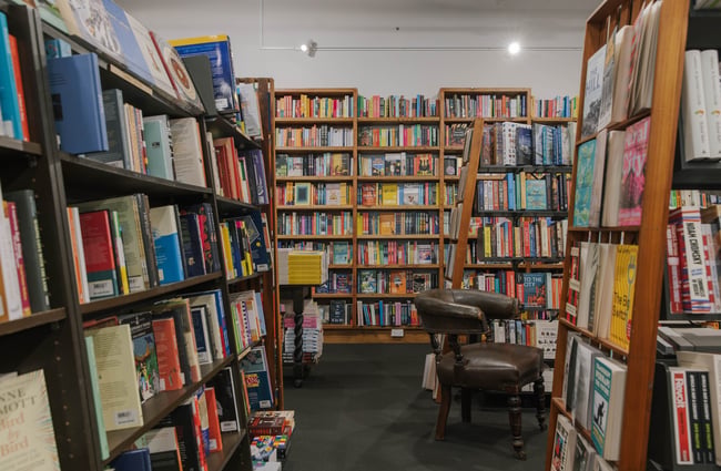 An empty armchair in the middle of bookcases filled with colourful titles in Scorpio Books.