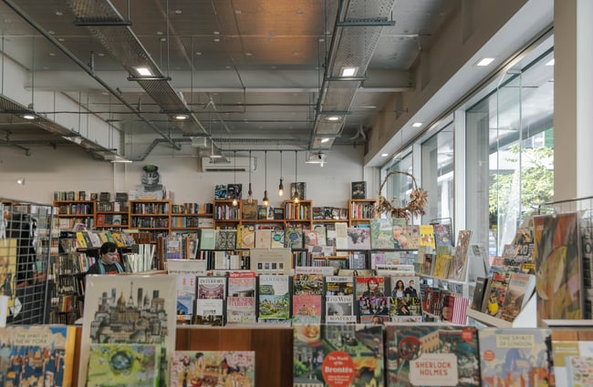 Exposed services and metal trays run along the ceiling above rows of bookcases.