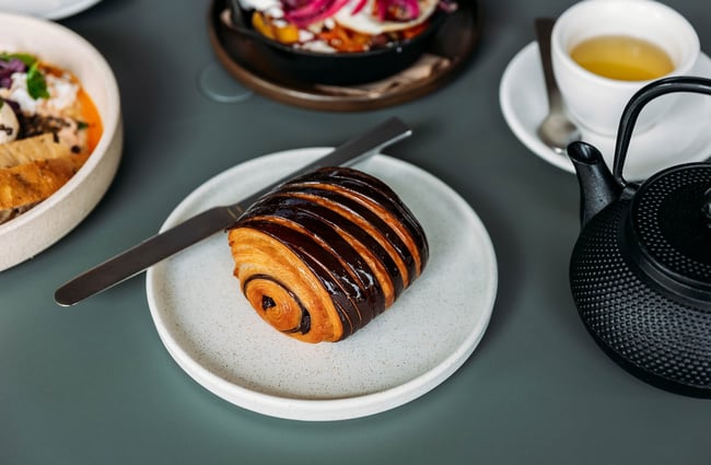 Close up of a brown-striped chocolate croissant on a plate on a table at Scroggin.