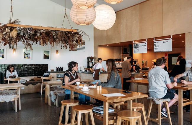 Scroggin's light and airy interior with people sitting at wooden tables below big, round, rice-paper lanterns.