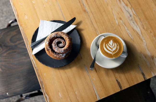 A coffee and cinnamon scroll on a table.
