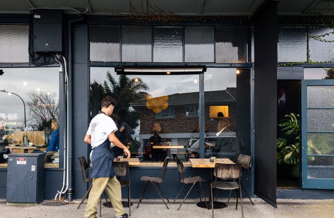 A staff member clearing tables outside Seabreeze Cafe Auckland.