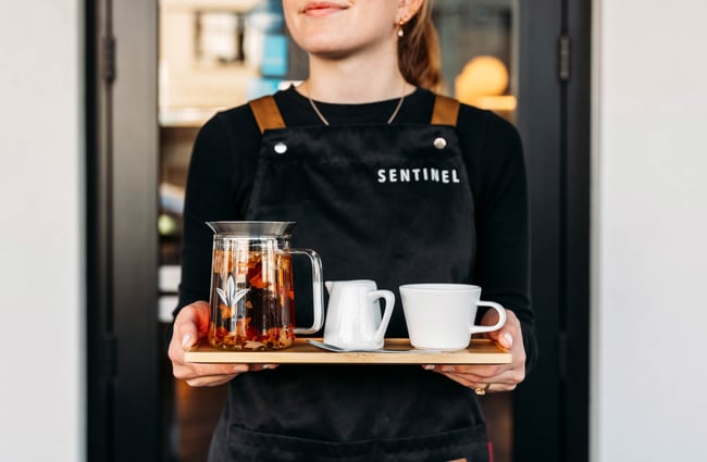 Barista delivering a tray of coffee at Sentinel Cafe in Hamilton.