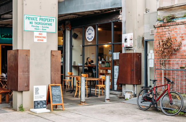 View of industrial brick laneway leading to Shelly Bay Baker on Leeds Street with two people sitting at window table