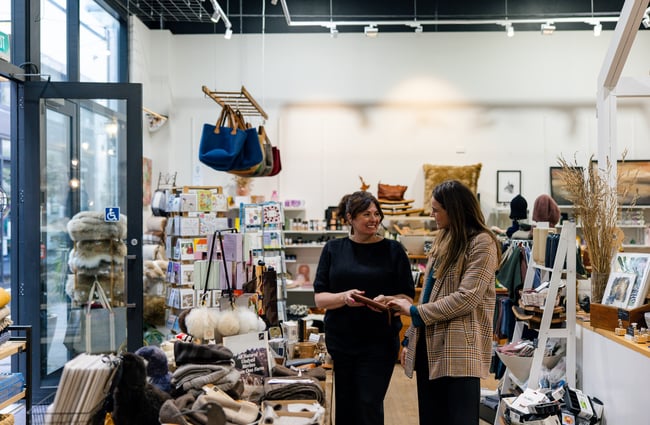 Two women are looking at different items on display at Shopology.