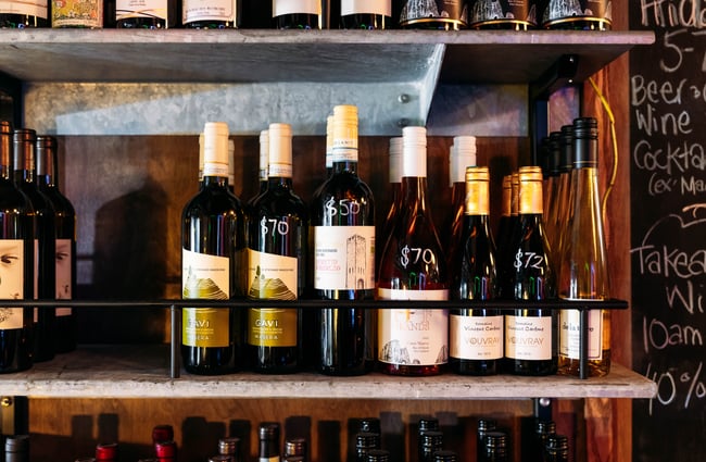 A close up of wine bottles on shelves inside a bar.