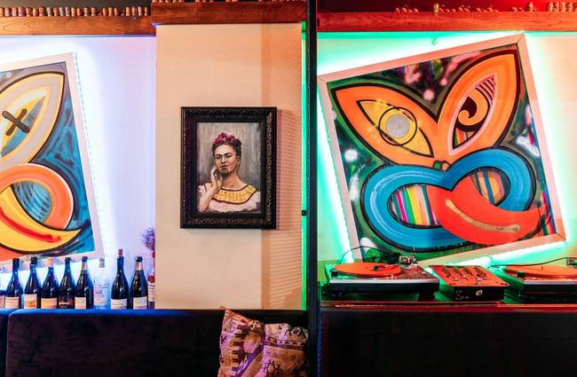A close up of painted works of art on a wall inside a dimly lit bar.
