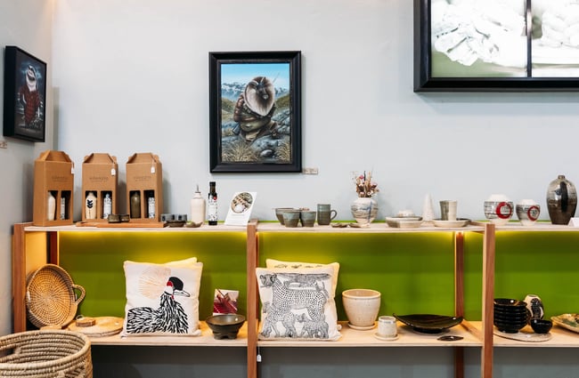 A selection of artworks, woven baskets, cushions and ceramic homewares on shelf