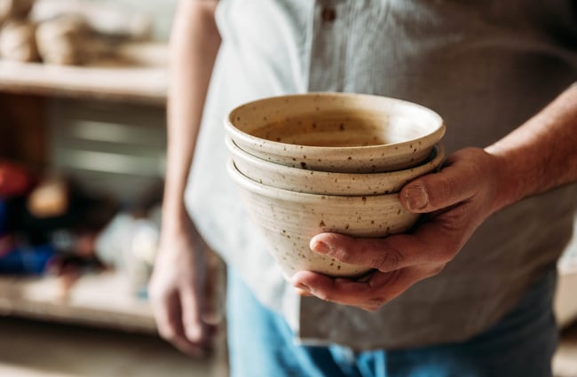 Potter holding a stack of three ceramic bowls