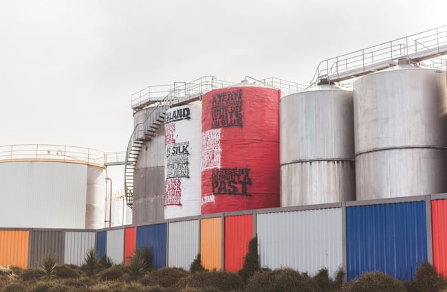 Coloured corrugated iron fencing by silos.