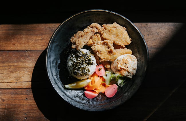 Fried chicken dish with rice and dipping sauce on table.